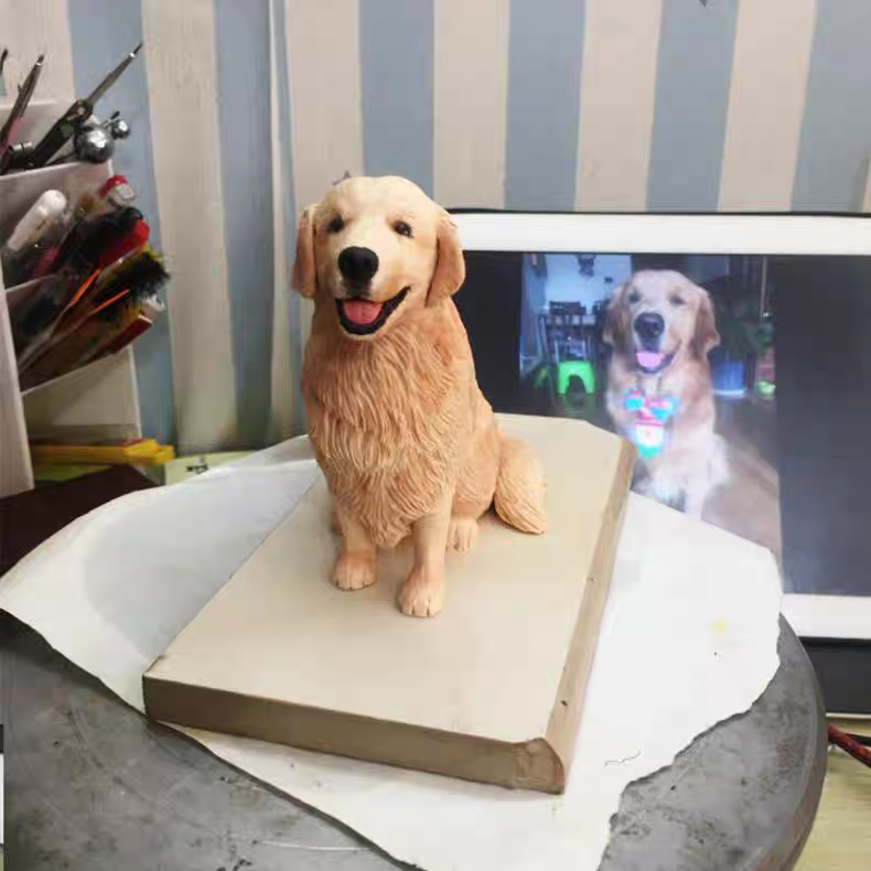 An adorable golden retriever, next to a small sculpture made of soft ceramic material exactly like her