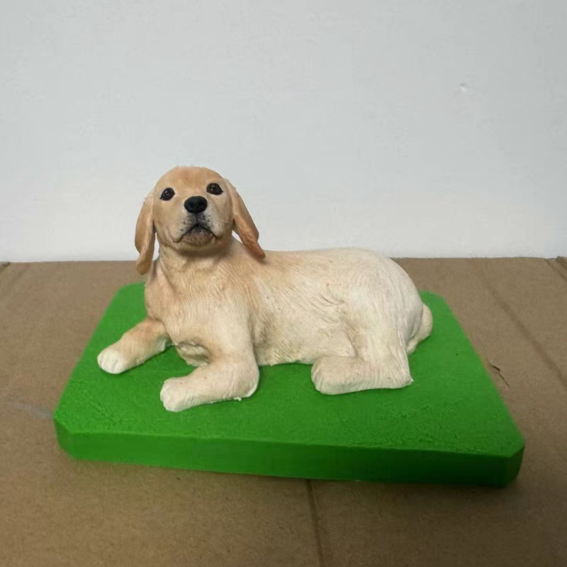 A soft ceramic sculpture of a golden dog lying on the ground