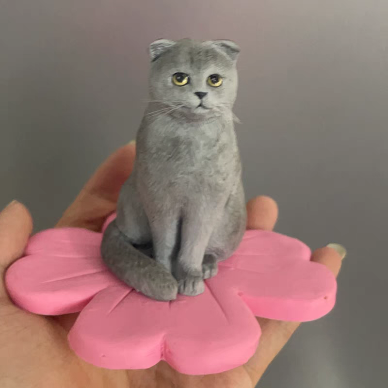 Soft ceramic sculpture of a cute gray cat sitting on a flower
