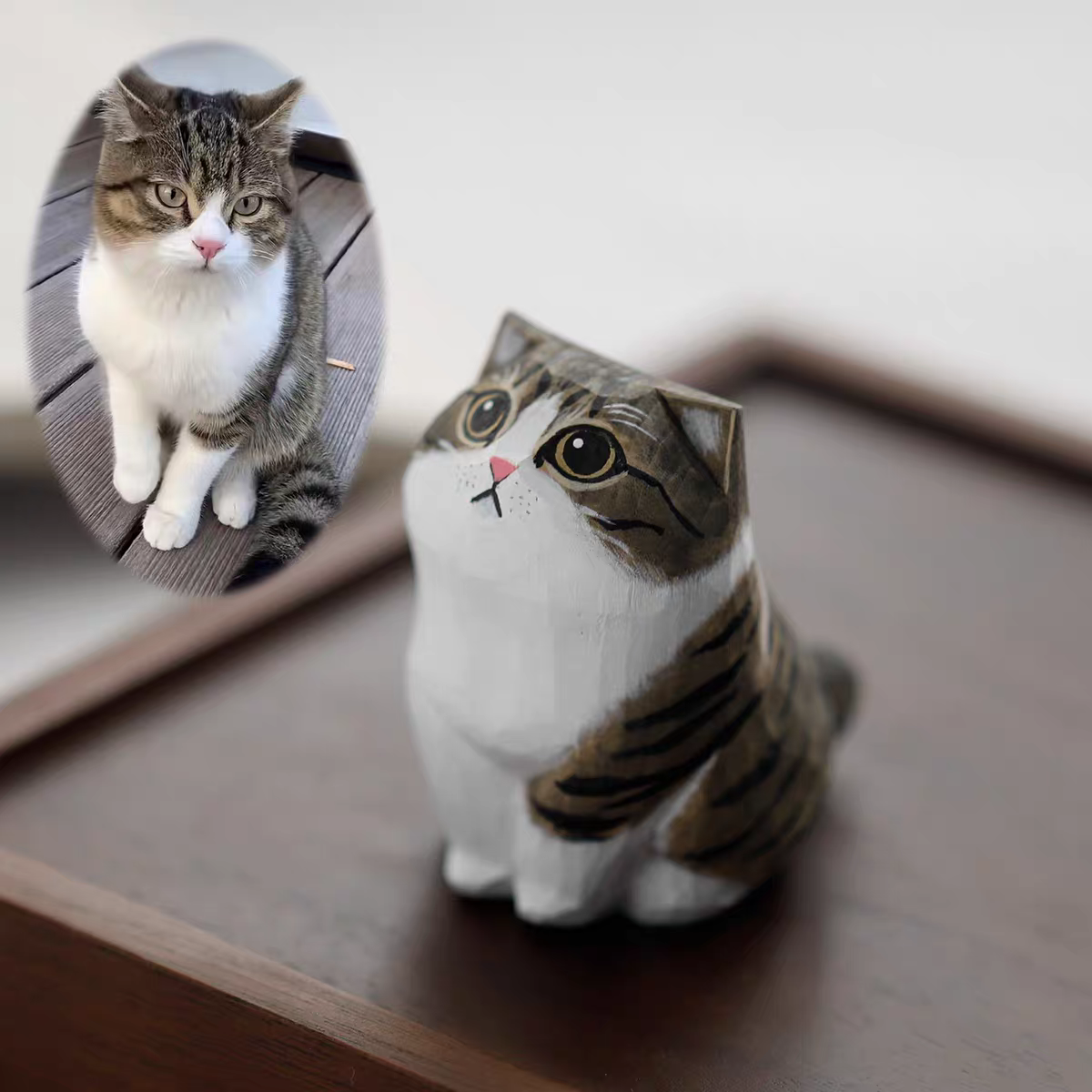 A fluffy, cute cat with a little wooden statue exactly like her next to it