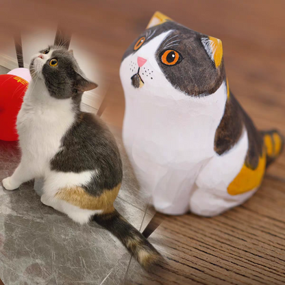 A fluffy, cute cat with a little wooden statue exactly like her next to it